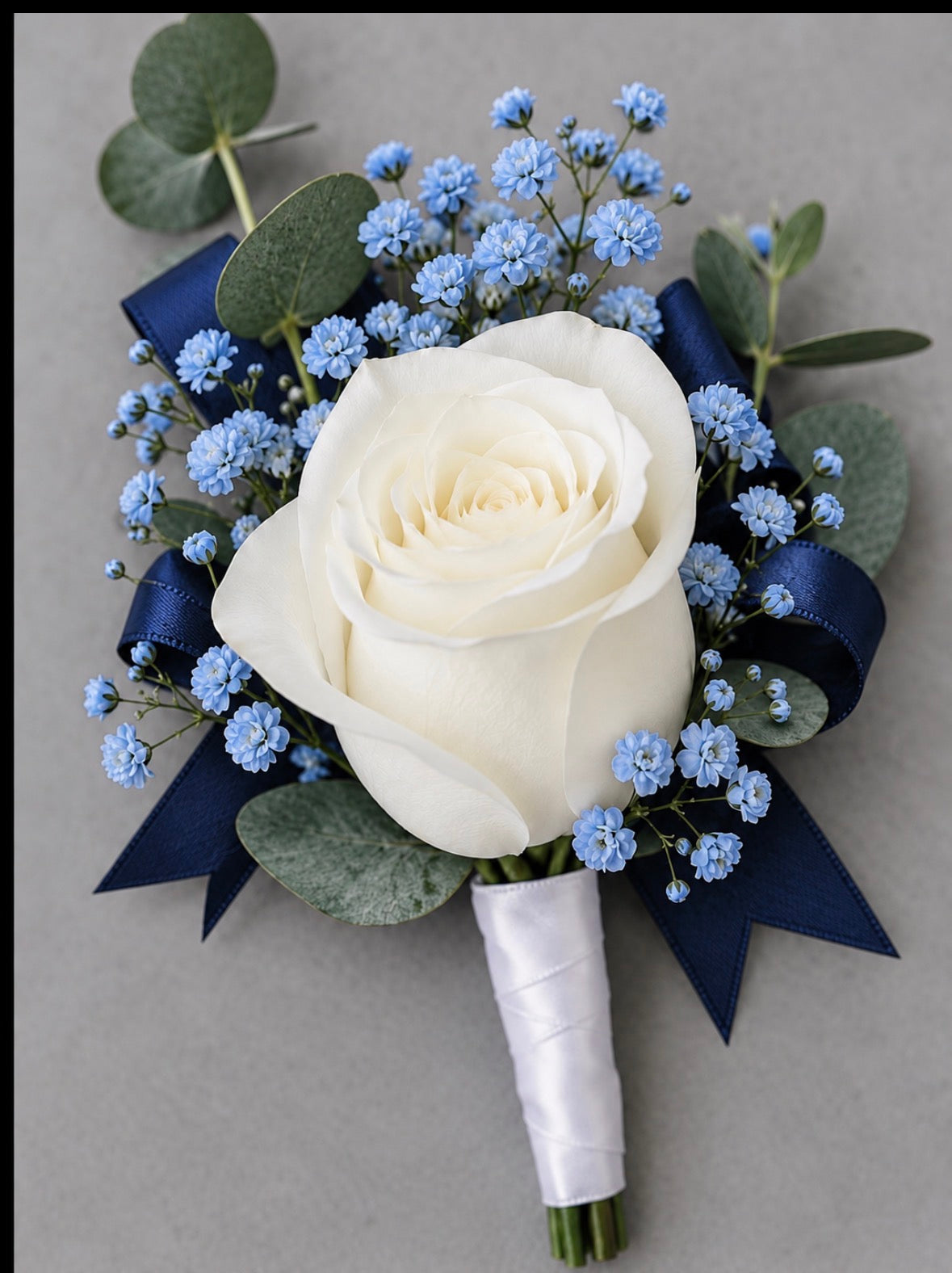 Blue matching boutonniere with white rose, blue accents and blue ribbon