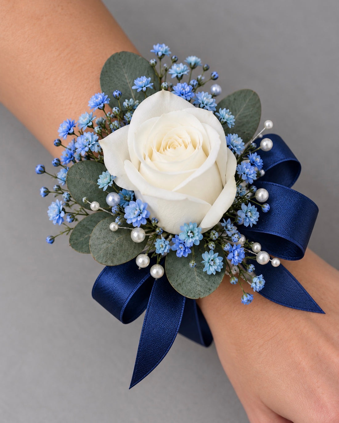 Blue wrist corsage with white rose, blue accents and blue ribbon